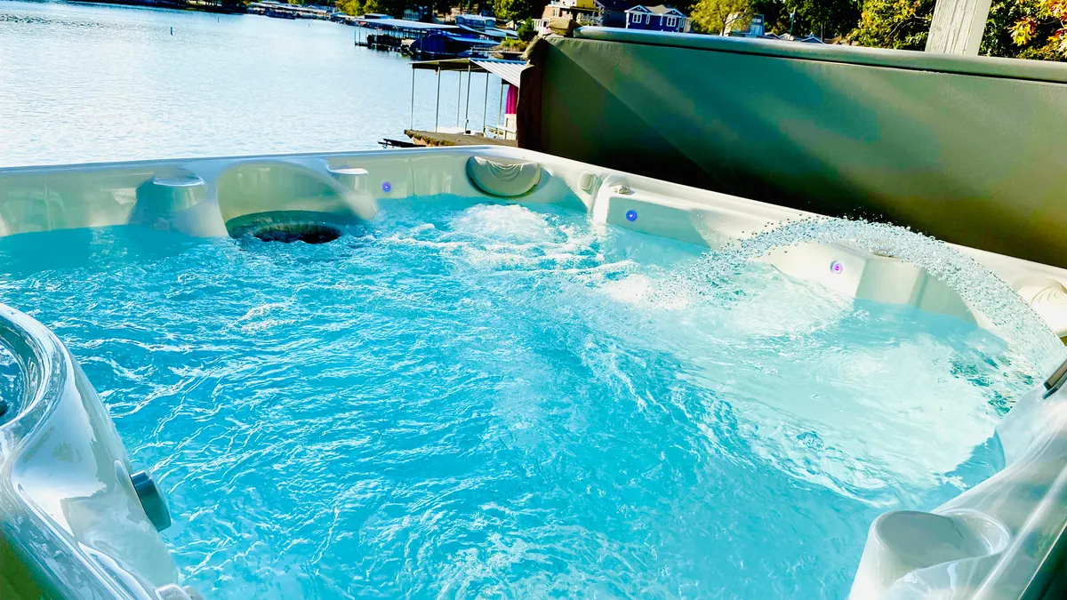 This image showcases a private hot tub overlooking calm water, with boats and a scenic landscape in the background. The tranquil setting invites socializing and relaxation, perfectly capturing the lakeside luxury and group-friendly amenities described in the section.