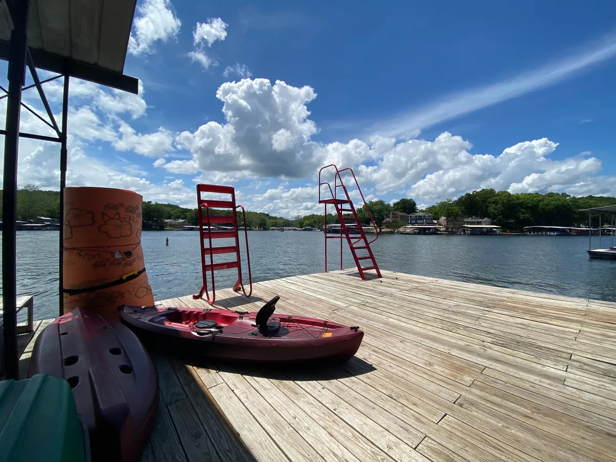 A relaxed yet adventurous lakeside setting featuring several red kayaks, red ladders leading into the water, and a yellow buoy. The scene glows with the warm colors of sunset, evoking memories of long, fun-filled days spent on the water with loved ones.