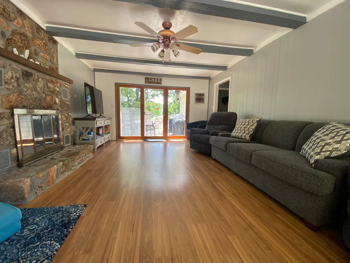 A cozy common area featuring a prominent stone fireplace, a plush sofa set, and expansive windows that fill the room with natural light. The space feels welcoming and designed for relaxation, with décor that blends comfort and style.
