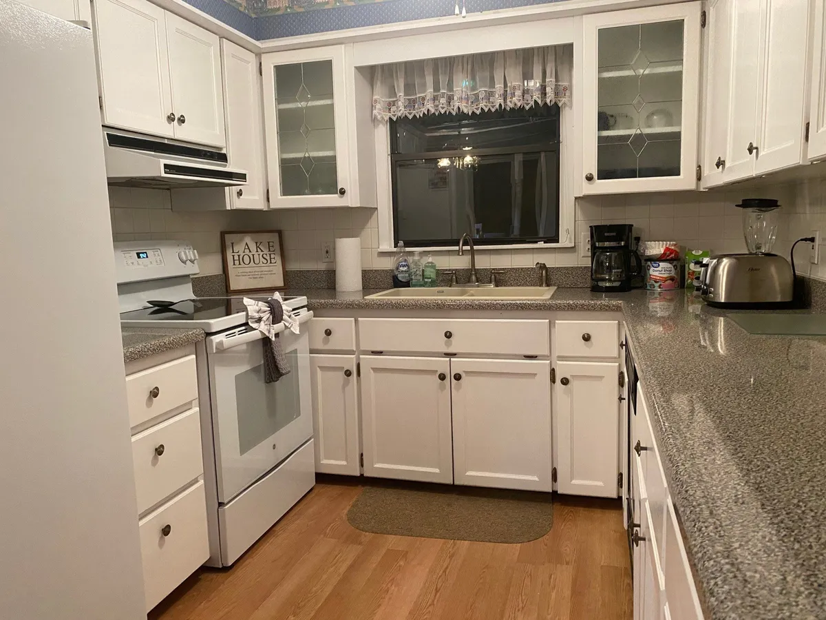 A fully stocked kitchen with a prominent kitchen sink, cooking stove, window with curtain, and welcoming countertop decor. The space looks ready for family cooking, baking, and casual conversation, echoing the ease of vacation meal prep.