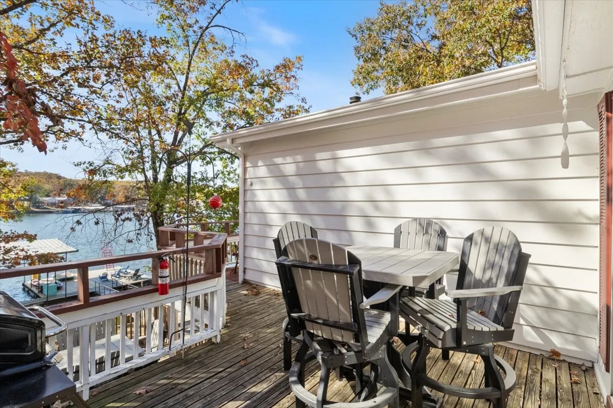 The image features an outdoor dining table with a stunning lake view and trees framing the scene. The table is set for a casual gathering, evoking the experience of shared meals and outdoor celebrations described in the section.
