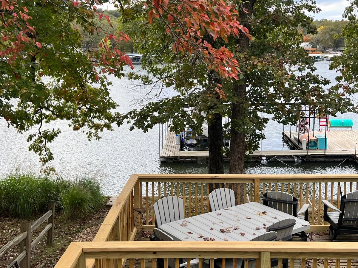 An inviting outdoor dining area set by the water’s edge, encircled by mature trees and open lake views. The table is ready for meals, coffee, or planning the day’s adventures, with docks visible in the background.